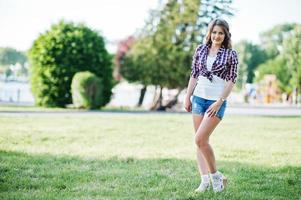retrato de una chica de campo con estilo en pantalones vaqueros cortos y camisa de línea a cuadros de campo traviesa foto