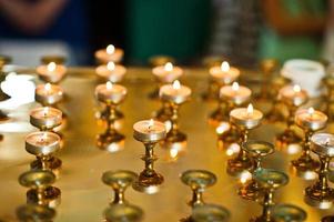 Row of burning circle candles on a golden stand at church photo