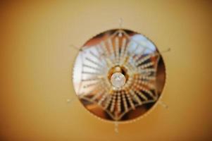 Golden and mirror chandelier on orange ceiling. Soft focus photo