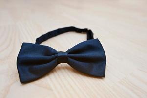 Silk blue bow tie on light wooden background photo