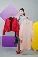 Young woman portrait with blank yellow and purple banner, board on gray isolated holding clothes at hands photo