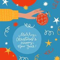 Xmas greeting card decorated with confetti, bauble, serpentine and stars. Female hand holding christmas tree decoration bauble. Flat Vector illustration isolated on blue background with lettering.