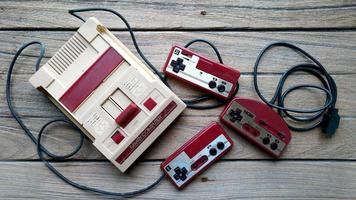 bangkok, tailandia - 10 de abril de 2019. viejo sistema de entretenimiento nintendo computadora familiar y controlador hori sobre fondo de madera. foto