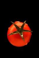 Cherry tomato in water drops isolated on black background. photo