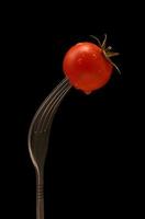 Cherry tomato on the fork. Water drops on the tomato. photo