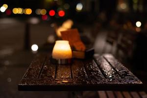 Burning candle on a wet wooden table after rain. photo