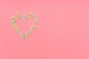 Heart of multicolored marshmallows isolated on pink background. photo