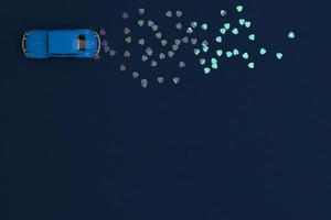 A blue toy car on a blue background leaves traces of hearts. photo