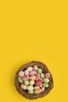 Multicolor decorated easter eggs in a nest on a yellow background. Isolated photo