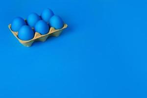 Six blue painted Easter eggs in yellow wrapping on blue background. Happy Easter holiday card or banner. Copy space. photo