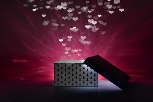 A magical box on a dark background with red lighting and heart bokeh. photo