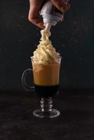 Viennese coffee with cream. The cream is poured by the male hand photo