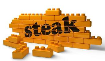 steak word on yellow brick wall photo