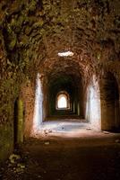 la luz del sol brilla a través del agujero del techo de ladrillo en el paso de la antigua fortaleza abandonada
