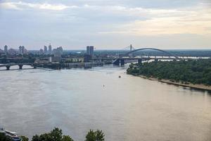 paisaje de la ciudad con puentes sobre el río dnipro contra el cielo nublado foto