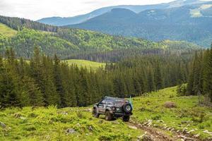 Scenic view of suv traveling towards forest against mountain range. photo