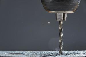 Metal drilling closeup in metal workshop on gray background. Hole being drilled into metal. photo