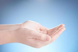 Close-up of beautiful woman hands, palms up. Isolated on blue background. Photo from copy space.