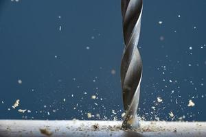 Wood drill bit in the blur with shaving on a gray background. Photo with copy space.