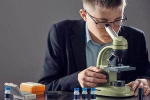 primer plano sobre el investigador que trabaja con microscopio en laboratorio. un tipo con gafas y chaqueta está trabajando con un microscopio. foto