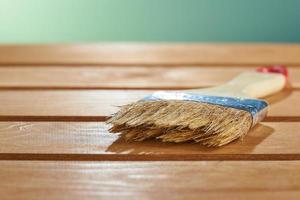 Varnishing natural wood with paint brush. Paint brush on a wooden surface. photo