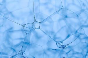 Soap foam close-up, like a gossamer. Blue abstract background. photo