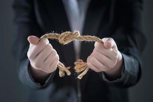 The businessman hands are trying to break the knot of the rope on the background of the suit in a blurry form. photo