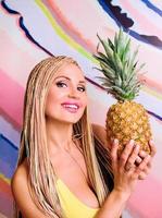 woman with african braids and with  pineapples in her hands in yellow dress photo