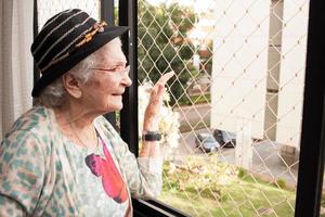 Elderly Lady at home Looking out the Window of her Apartment photo