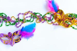 Two carnival masks with feathers and multi-colored beads on white background. photo