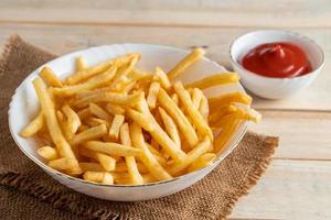 Hot golden french fries with ketchup on a wooden background. photo
