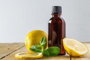 Aromatic oil with lemon and mint on wooden background. photo