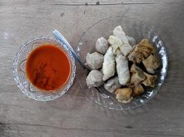 close up of meatball with sauce on plate. with a wooden background. photo