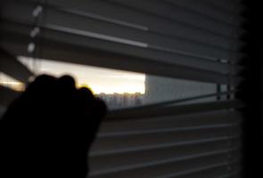 Dawn over the city. A hand from a dark apartment opens the blinds. An abstraction of hope.