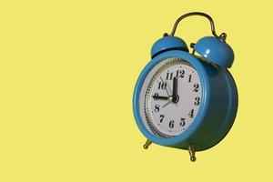 Blue alarm clock with copy space on a yellow background. photo