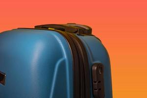Blue Suitcase on an Orange Background. Summer Travel Concept. photo
