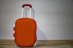 Travel Children's Plastic Suitcase on a Light Background. The Little Child's Luggage Stands Against the Wall and Ready to Go on Vacation. photo
