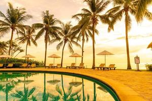 sombrilla y silla alrededor de la piscina en el hotel resort para viajes de placer y vacaciones cerca del mar océano playa foto