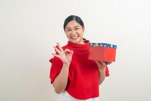 happy Asian woman wearing red shirt with gift box on hand for Christmas festival photo