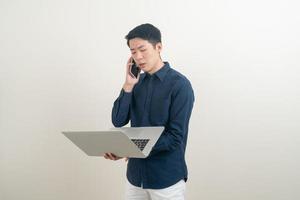 Asian man talking smartphone or mobile phone and hand holding laptop photo