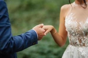 the bride and groom tenderly hold hands photo