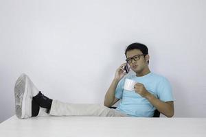 un joven asiático se sorprendió cuando miró un teléfono inteligente con una pierna sobre la mesa foto