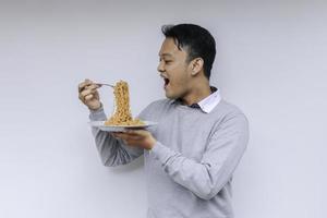 retrato de shock y wow joven asiático disfruta de fideos. comer el concepto de almuerzo. foto