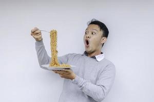 retrato de shock y wow joven asiático disfruta de fideos. comer el concepto de almuerzo. foto