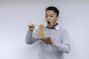 Portrait of Shock and Wow Young Asian man enjoy noodles. Eating lunch concept. photo