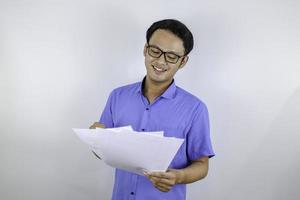 Young Asian Man is smile and happy when looking on paper document. Indonesian man wearing blue shirt. photo