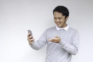 Young Asian man shocked and happy with what he see in the smartphone on isolated grey background. photo