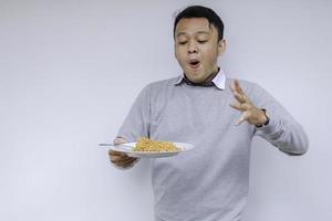 retrato de shock y wow joven asiático disfruta de fideos. comer el concepto de almuerzo foto