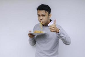 el joven asiático disfruta de los fideos. comer el concepto de almuerzo. foto