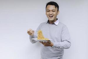 Portrait of happy Young Asian man enjoys noodles. Eating lunch concept. photo